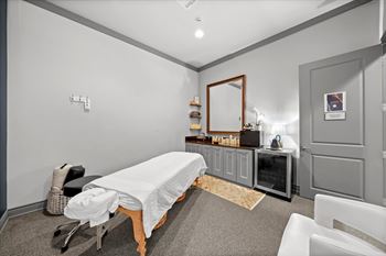 A room with a massage table and a mirror on the wall.